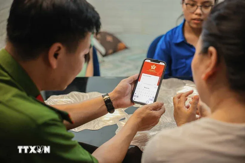 A police officer helping a resident use VNeID on her phone